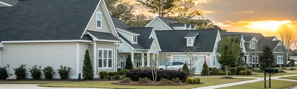 A street view of a new construction neighborhood with larger landscaped homes and houses with yards and sidewalks taken near sunset with copy space