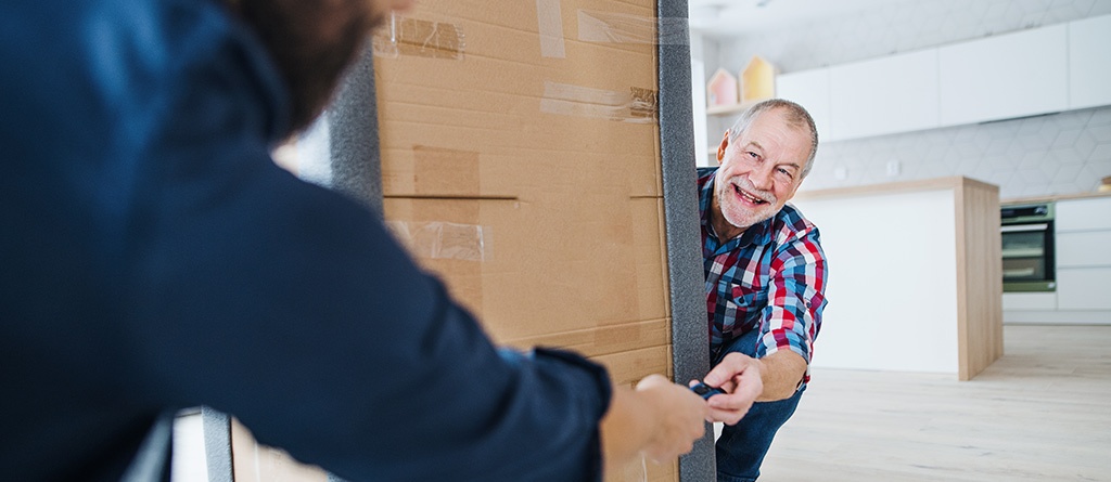 A cheerful senior man helping his mature son with furnishing new house, a new home concept.