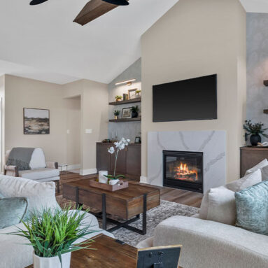 Parade of Homes model, The Lexi, great room with large grey couches and welcoming warm fireplace. Featuring two built-in with showcase personal items