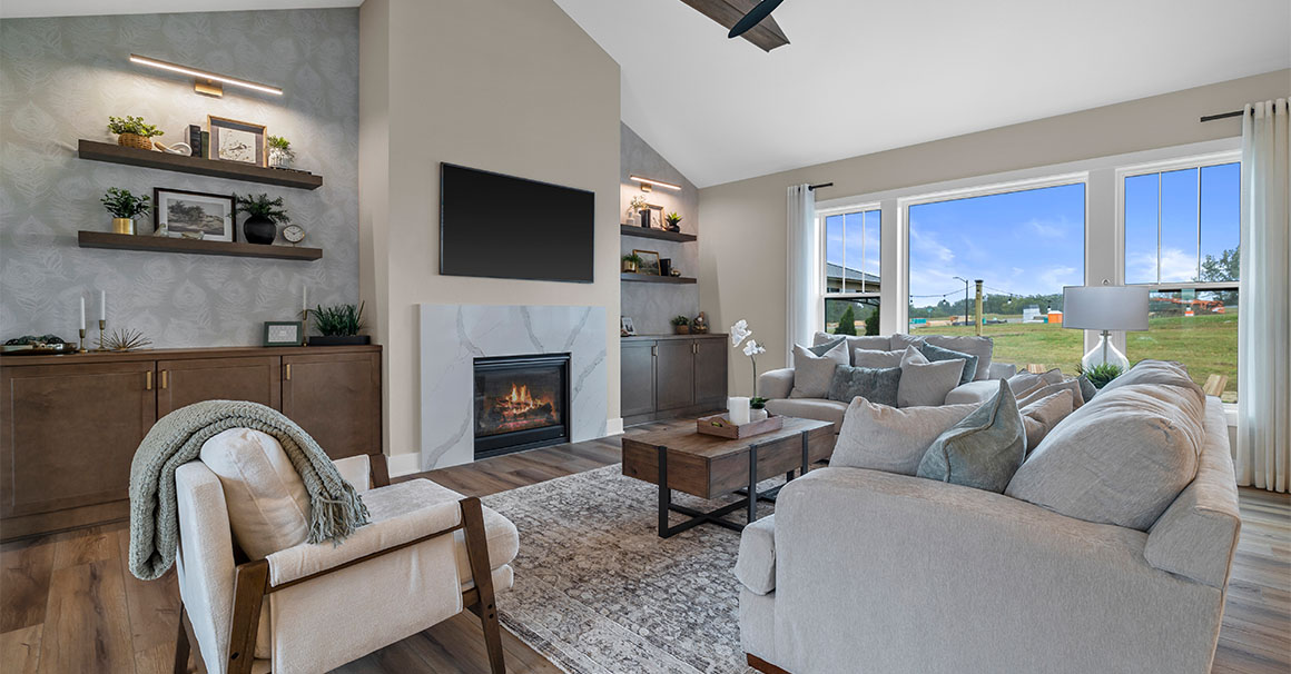 Parade of Homes model, The Lexi, great room with large grey couches and welcoming warm fireplace. Featuring two built-in with showcase personal items