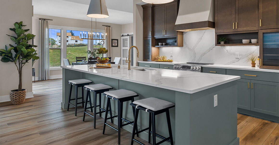 Parade of Homes model, The Lexi, kitchen featuring bright white counter tops, dark green grey lowers, and wood uppers. All the fine details feature bright gold.