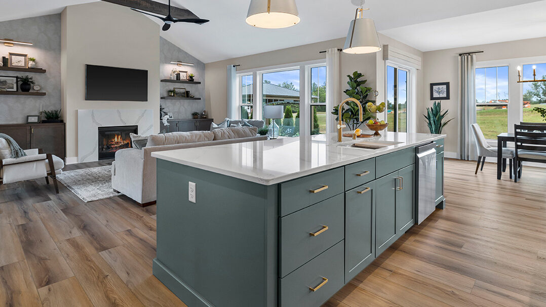 Parade of Homes model, The Lexi, kitchen featuring bright white counter tops, dark green grey lowers, and wood uppers. This angle looks at the great room.