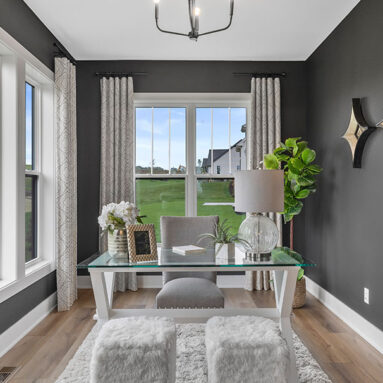 Parade of Homes model, The Lexi, flex room that is staged as an at home office. This room features dark walls with constrating white trim.